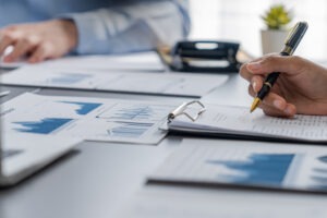 Mehrere Personen prüfen am Besprechungstisch Unterlagen mit Tabellen und Diagrammen – Symbolbild zum PCGK Bericht und zur Corporate Governance der ALDB GmbH